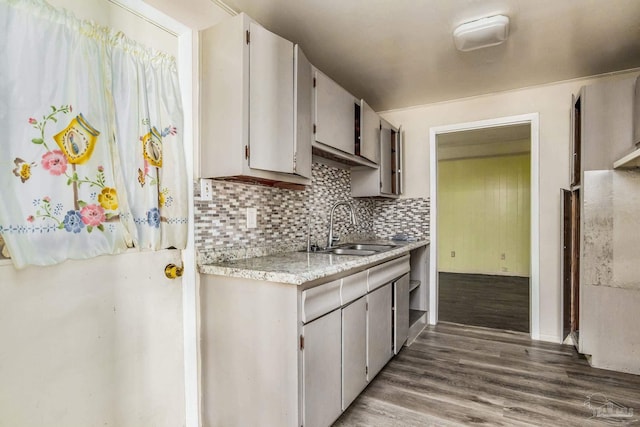 kitchen with light countertops, a sink, backsplash, and wood finished floors