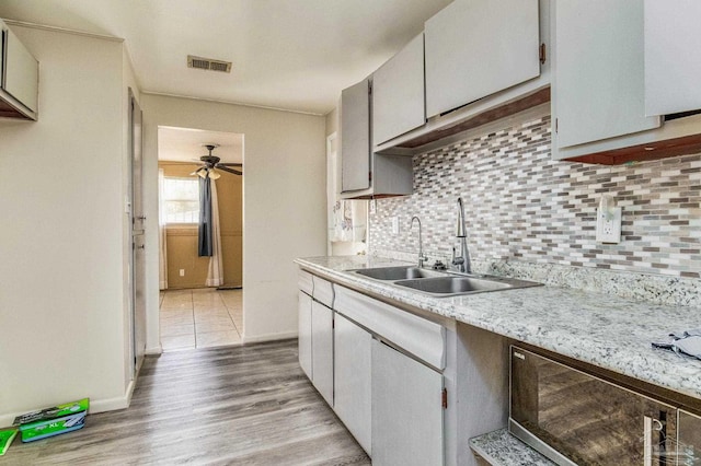 kitchen featuring a sink, visible vents, light countertops, light wood-type flooring, and backsplash