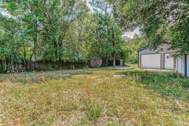 view of yard featuring an outbuilding, a detached garage, and fence