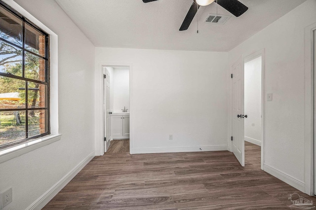 unfurnished bedroom with visible vents, dark wood-type flooring, a ceiling fan, connected bathroom, and baseboards