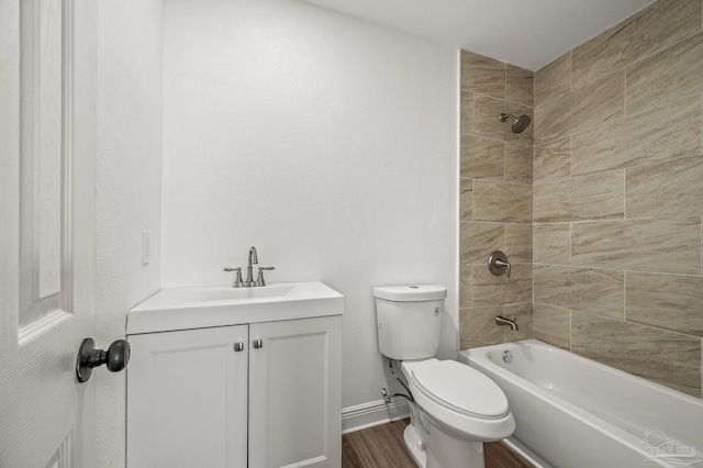 bathroom with vanity, wood finished floors, baseboards,  shower combination, and toilet