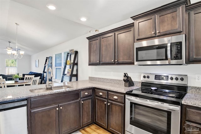 kitchen featuring dark brown cabinetry, stainless steel appliances, lofted ceiling, and sink