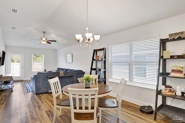 dining space with vaulted ceiling, hardwood / wood-style floors, and ceiling fan with notable chandelier