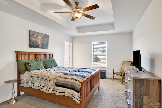 carpeted bedroom with a tray ceiling and ceiling fan