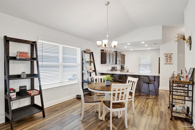 dining room featuring plenty of natural light, an inviting chandelier, light wood-type flooring, and vaulted ceiling