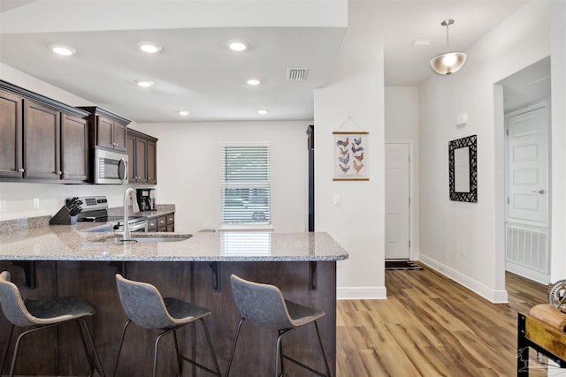 kitchen with kitchen peninsula, light wood-type flooring, a breakfast bar, and stainless steel appliances