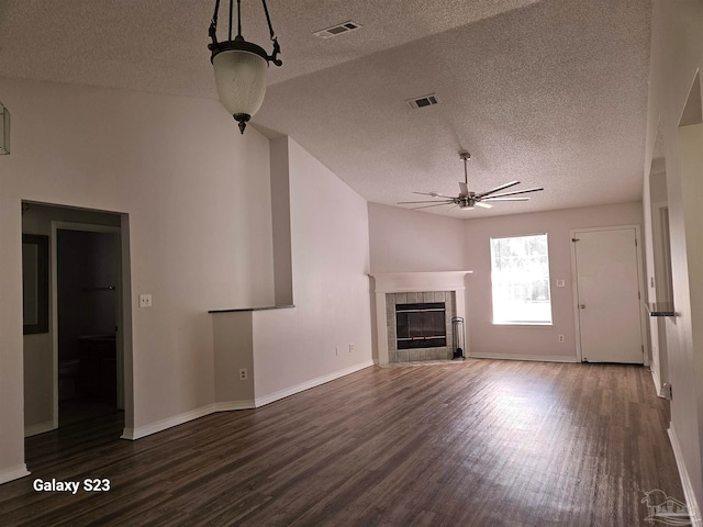 unfurnished living room with a fireplace, dark hardwood / wood-style flooring, a textured ceiling, and vaulted ceiling