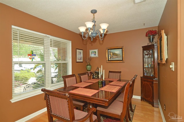 5845 Keystone Rd, Pensacola, FL 32504 - dining area with plenty of natural light, a chandelier, baseboards, light wood-style flooring, and a textured ceiling