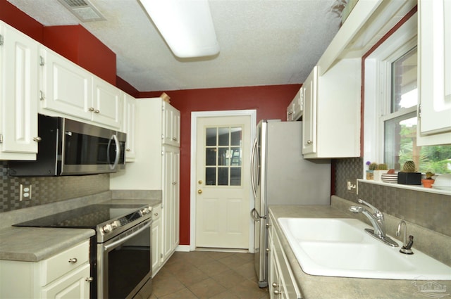 5845 Keystone Rd, Pensacola, FL 32504 - kitchen featuring appliances with stainless steel finishes, a sink, backsplash, dark tile patterned floors, and white cabinets