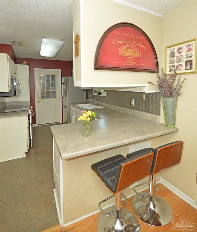 5845 Keystone Rd, Pensacola, FL 32504 - kitchen with a sink, white cabinets, a peninsula, decorative backsplash, and a textured ceiling