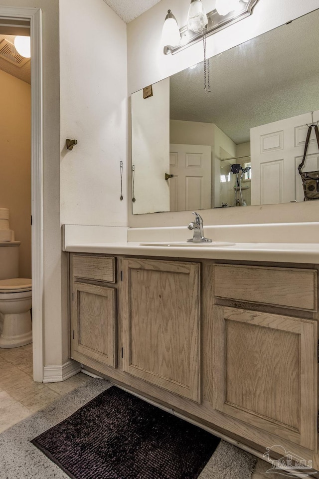 bathroom featuring a textured ceiling, vanity, a shower, tile patterned flooring, and toilet