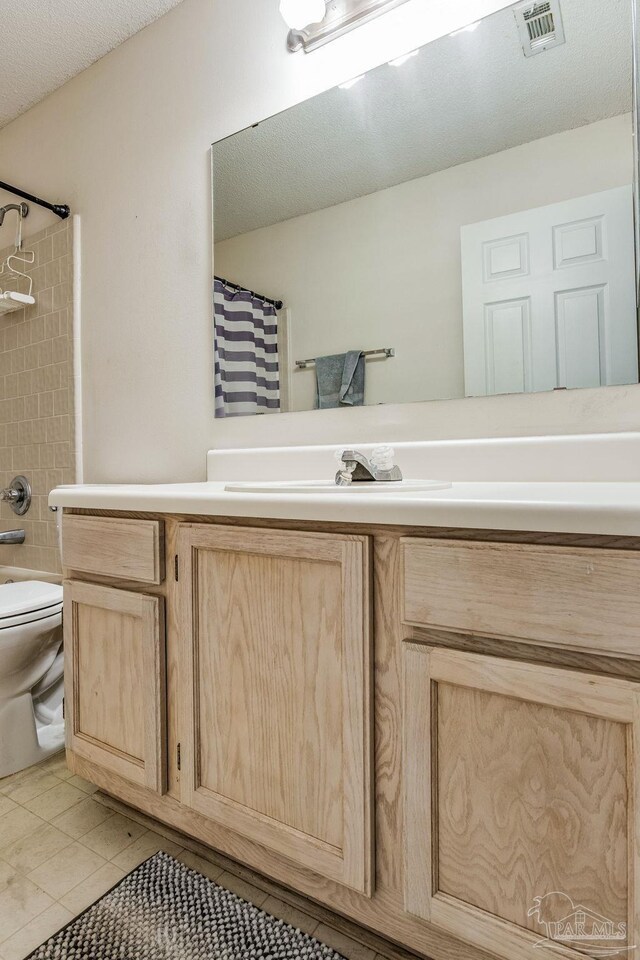 bathroom featuring tile patterned flooring, vanity, a textured ceiling, and toilet