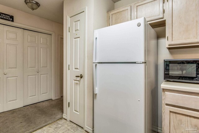 kitchen featuring light carpet, light brown cabinetry, and white refrigerator