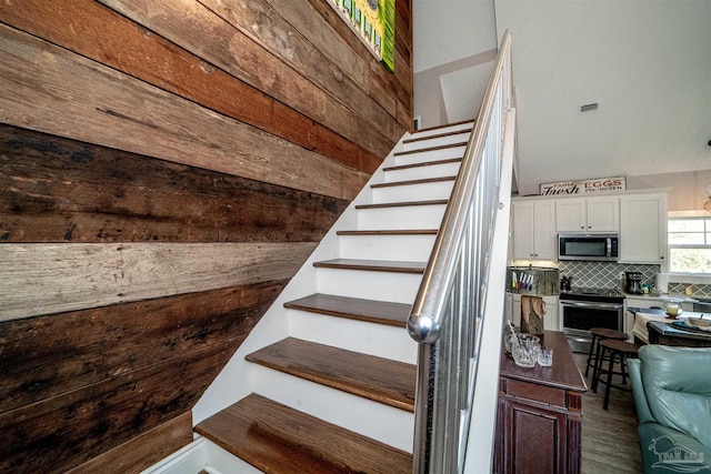 stairway with hardwood / wood-style floors and wood walls