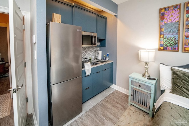 kitchen with decorative backsplash, stainless steel appliances, blue cabinetry, and sink