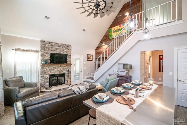 living room with a stone fireplace and high vaulted ceiling