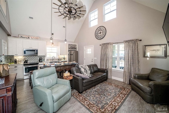 living room featuring light wood-type flooring and high vaulted ceiling