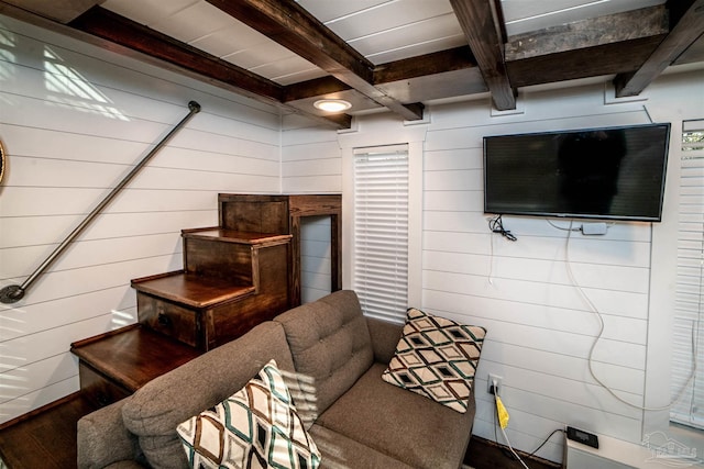 living room with beamed ceiling and wooden walls