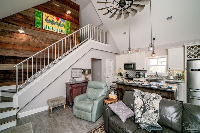 living room with hardwood / wood-style floors, sink, and high vaulted ceiling