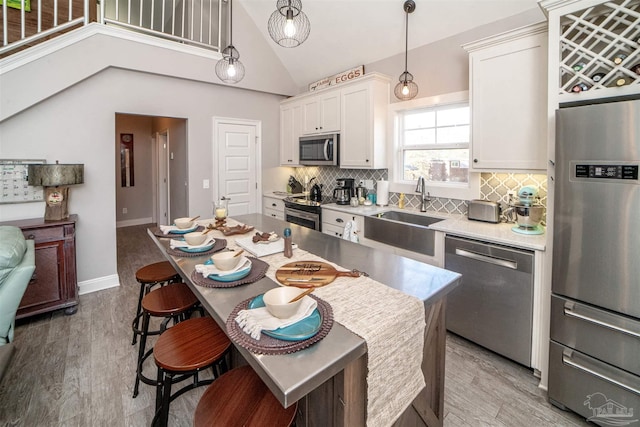 kitchen with white cabinetry, sink, hanging light fixtures, tasteful backsplash, and appliances with stainless steel finishes