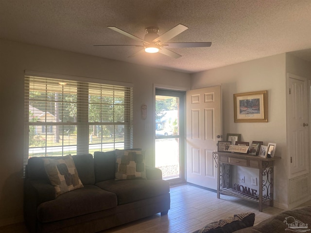 living room featuring a textured ceiling, a healthy amount of sunlight, hardwood / wood-style flooring, and ceiling fan