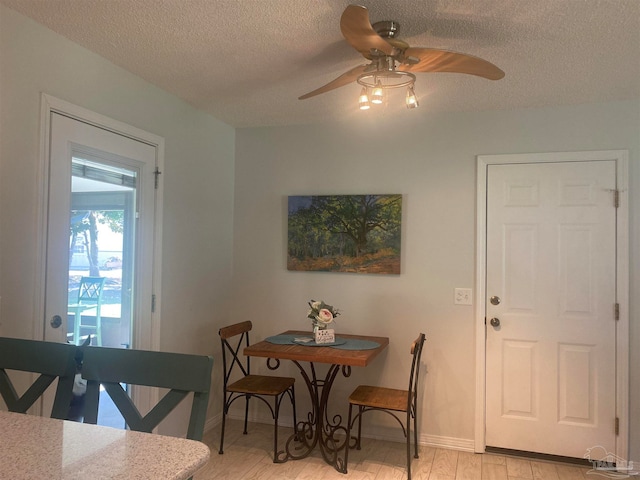 dining space with ceiling fan, a textured ceiling, and light wood-type flooring