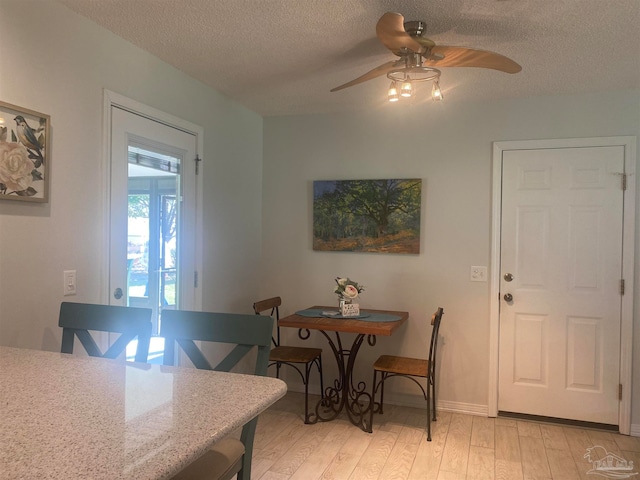 dining space with light hardwood / wood-style floors, a textured ceiling, and ceiling fan