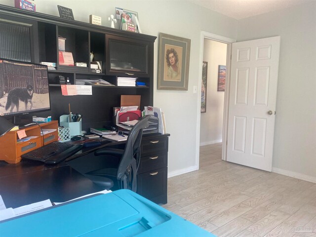 home office with light hardwood / wood-style flooring