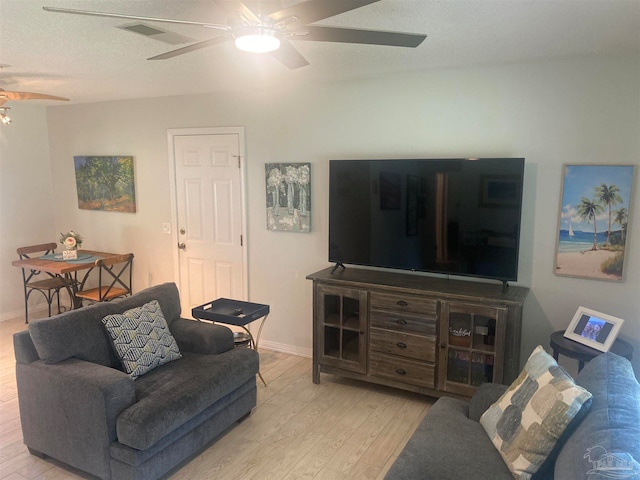 living room with a textured ceiling, light hardwood / wood-style floors, and ceiling fan