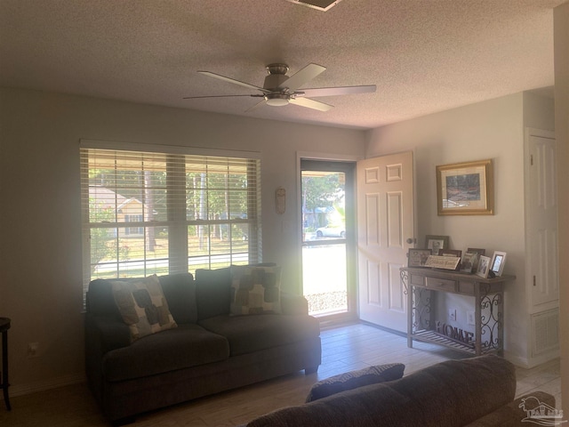 living room featuring ceiling fan, hardwood / wood-style flooring, and a textured ceiling