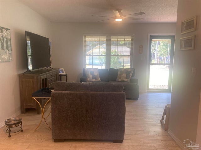 living room with a textured ceiling, light hardwood / wood-style floors, and ceiling fan