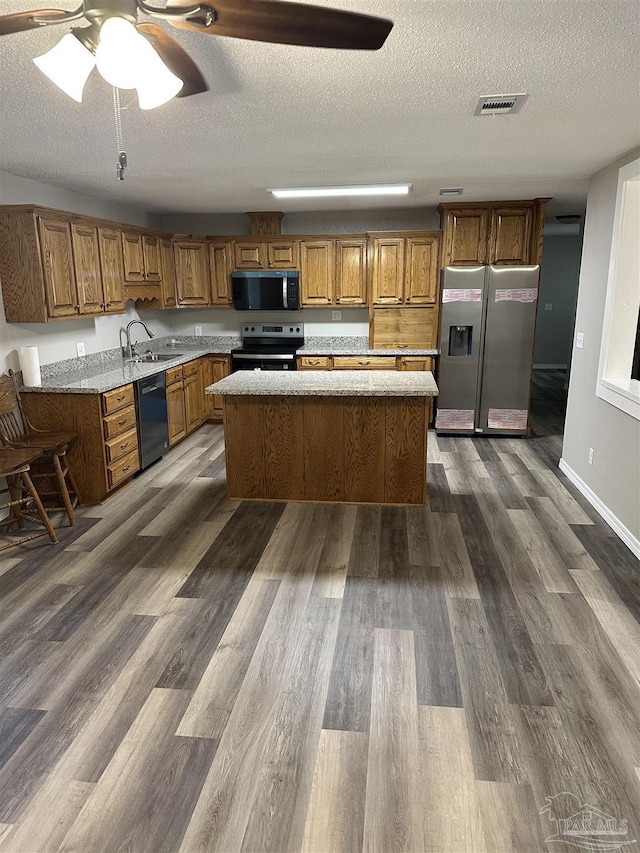 5303 Mikes Pl, Milton, FL 32570 - kitchen with dark wood-style floors, visible vents, brown cabinets, and appliances with stainless steel finishes