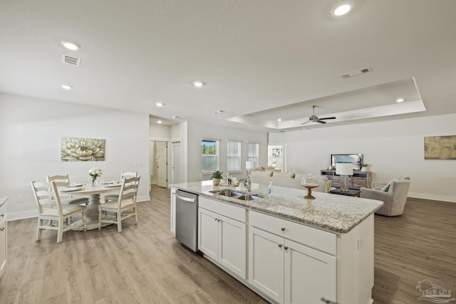 kitchen featuring a kitchen island with sink, stainless steel dishwasher, white cabinets, sink, and a raised ceiling