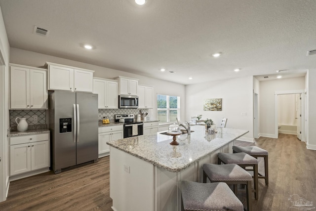 kitchen with white cabinetry, sink, an island with sink, stainless steel appliances, and a breakfast bar area