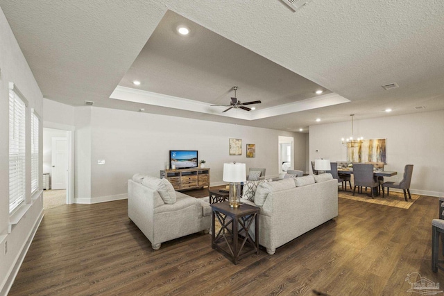 living room featuring ceiling fan with notable chandelier, a raised ceiling, dark hardwood / wood-style floors, and a textured ceiling