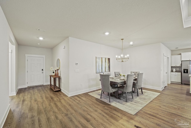 dining space featuring wood-type flooring, a textured ceiling, and an inviting chandelier