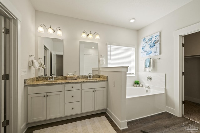 bathroom with hardwood / wood-style floors, a bathing tub, and vanity