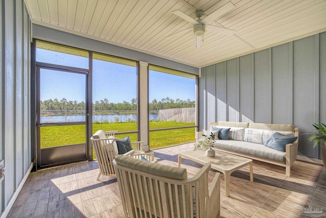 sunroom with ceiling fan and a water view