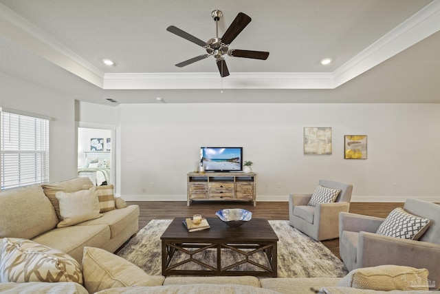 living room featuring wood-type flooring, crown molding, and a tray ceiling