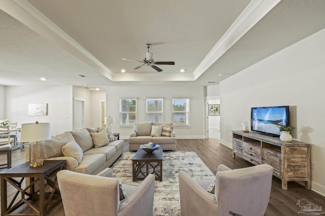 living room with ceiling fan, a raised ceiling, crown molding, and dark hardwood / wood-style flooring