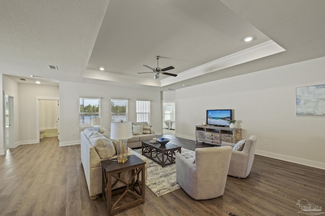 living room with ceiling fan, hardwood / wood-style floors, a tray ceiling, and a textured ceiling