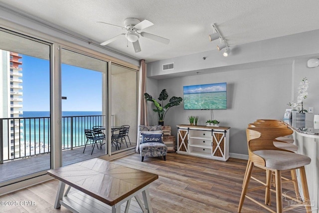 interior space featuring a ceiling fan, wood finished floors, a textured ceiling, rail lighting, and visible vents