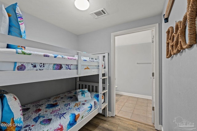 bedroom with baseboards, wood finished floors, and visible vents