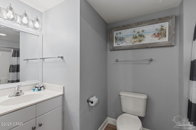 full bath featuring toilet, vanity, and baseboards