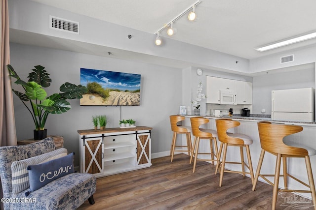 kitchen featuring white cabinets, visible vents, wood finished floors, and white appliances
