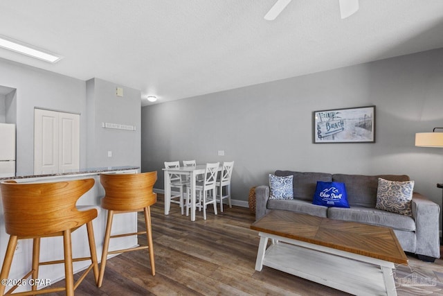 living area featuring wood finished floors, a ceiling fan, and baseboards