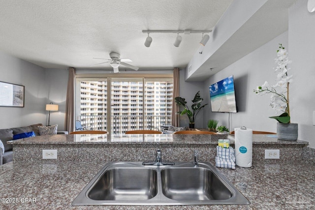 kitchen with track lighting, a ceiling fan, a sink, and a textured ceiling