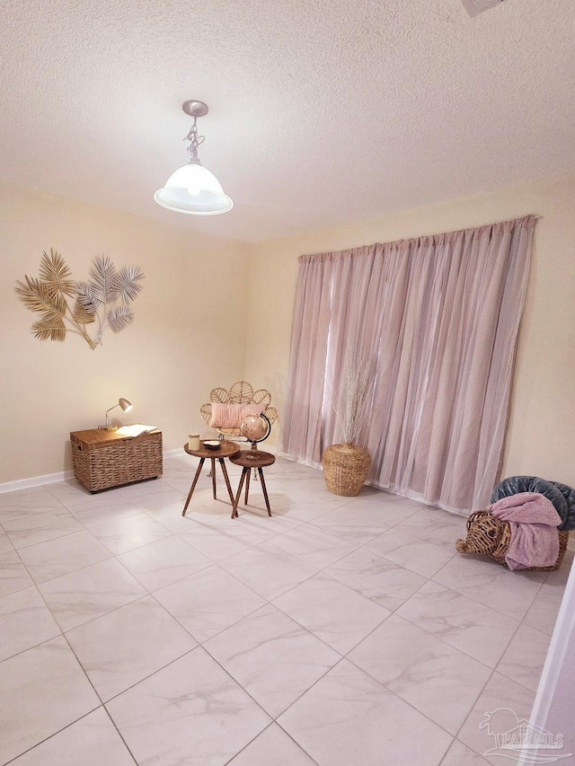 unfurnished room featuring a textured ceiling and baseboards