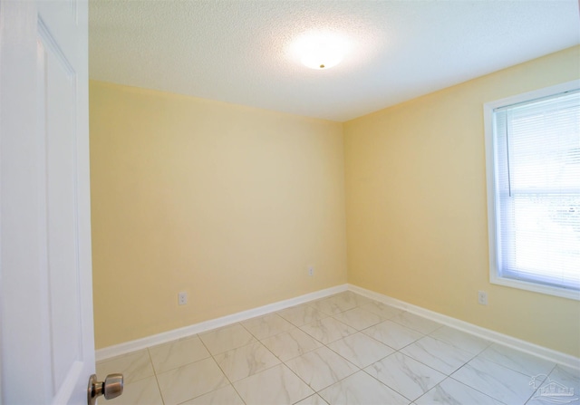 empty room with baseboards and a textured ceiling