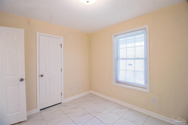 unfurnished room with a textured ceiling and baseboards